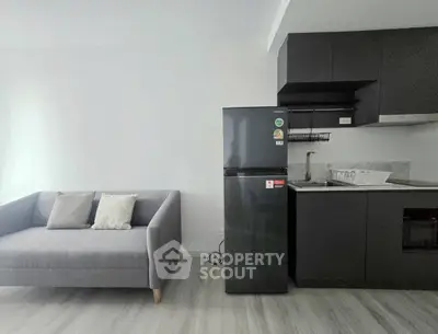 Modern apartment interior with sleek kitchen and cozy living area featuring a stylish sofa and contemporary appliances.