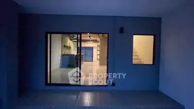 Modern entrance with sleek glass doors and illuminated staircase in contemporary building.