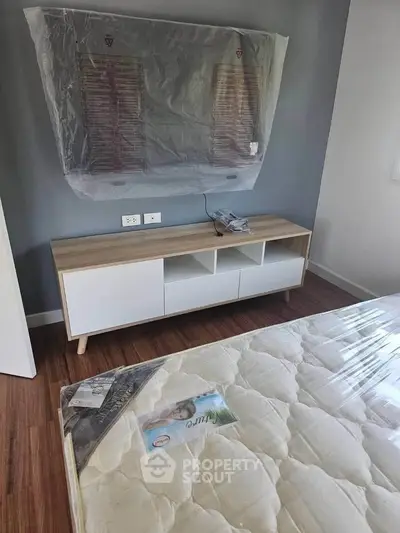 Modern bedroom with wooden flooring and stylish TV stand, featuring a comfortable mattress.