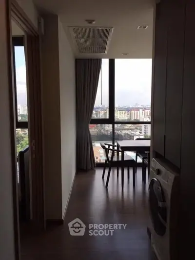 Modern apartment interior with washing machine and city view from large window.
