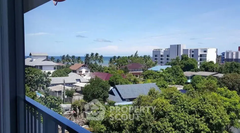 Stunning balcony view of lush greenery and ocean horizon in a serene neighborhood.