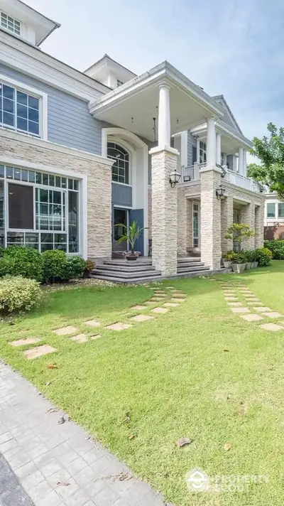 Elegant two-story house with stone facade and lush green lawn