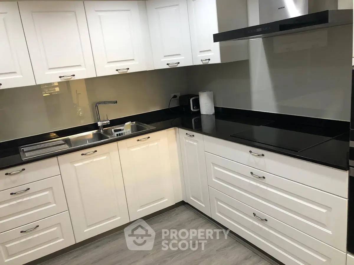 Modern kitchen with sleek white cabinets and black countertops
