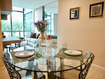 Modern dining area with glass table and stylish decor in a bright open-plan apartment.