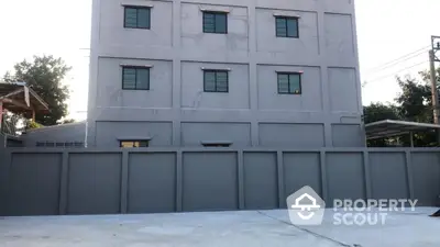 Modern gray building exterior with secure perimeter wall and spacious driveway