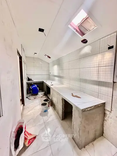 Spacious kitchen under renovation with modern tile flooring and ample counter space.