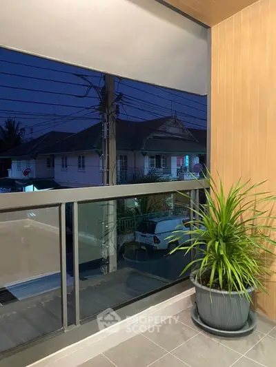 Charming balcony with potted plant and evening view of residential neighborhood.
