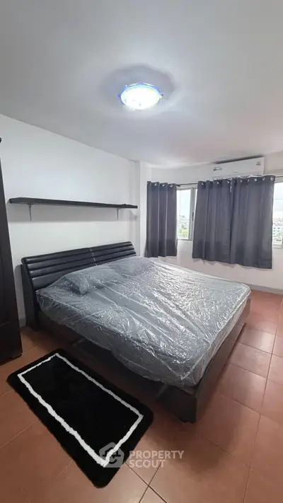 Spacious bedroom with modern bed and large windows offering natural light.