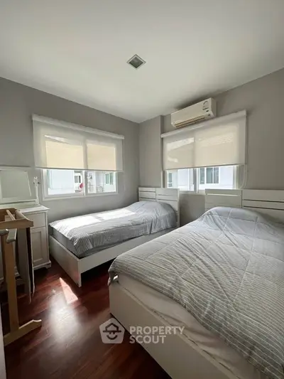 Cozy bedroom with twin beds and natural light, perfect for relaxation.