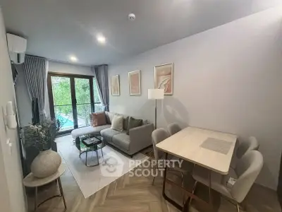 Modern living room with stylish decor and dining area, featuring large windows and cozy seating.