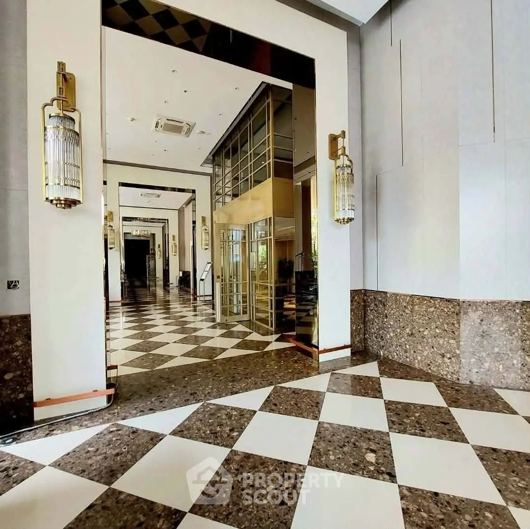 Luxurious building entrance with elegant checkered flooring and modern lighting fixtures.