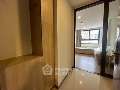 Modern apartment entrance leading to a bright bedroom with large window view.
