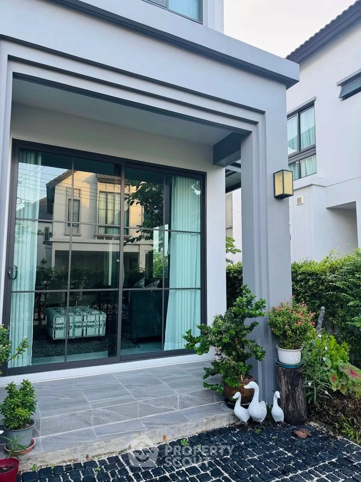 Modern house exterior with large windows and garden decor