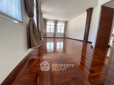 Spacious living room with polished wooden floors and large windows.