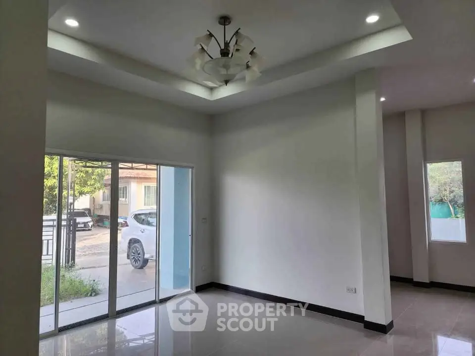 Spacious modern living room with large windows and elegant ceiling light fixture.