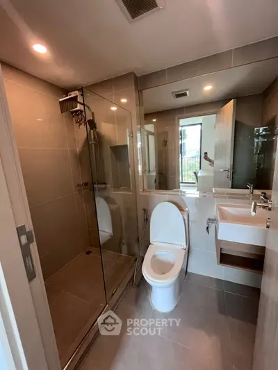Modern bathroom with glass shower and sleek fixtures in a contemporary apartment.