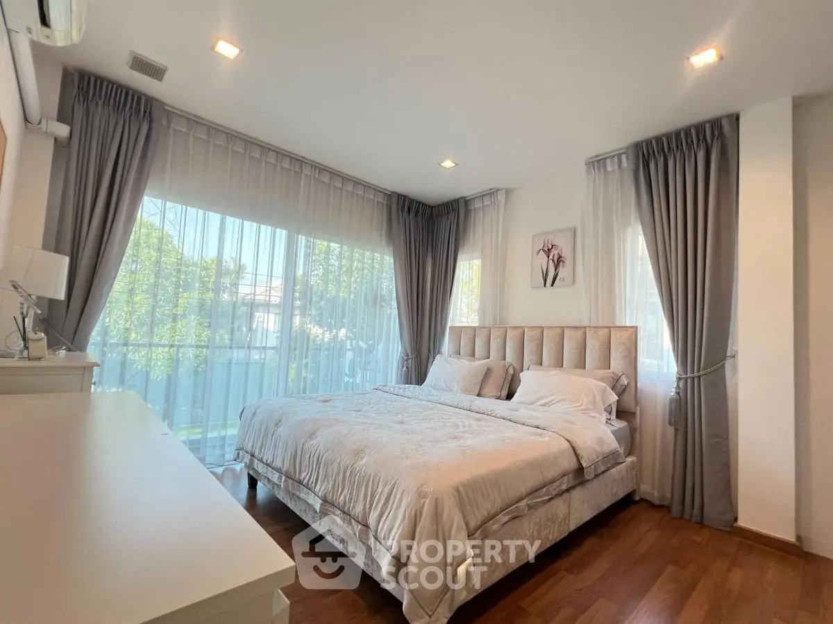 Elegant bedroom with large windows and luxurious bedding in a modern home.