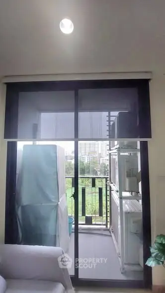 Modern apartment balcony with city view and laundry area, featuring sliding glass doors and natural light.