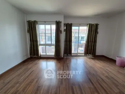 Spacious empty room with wooden floors and large windows