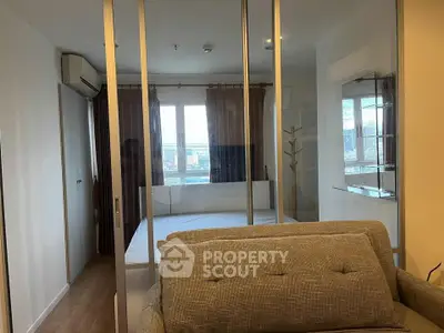 Modern bedroom with glass partition and city view, featuring cozy sofa and air conditioning.