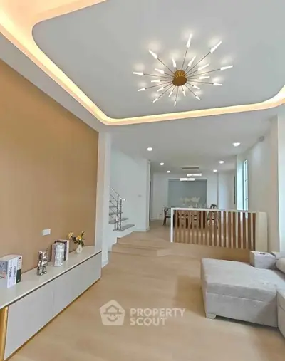 Modern living room with stylish lighting and open layout, featuring elegant staircase and cozy seating area.