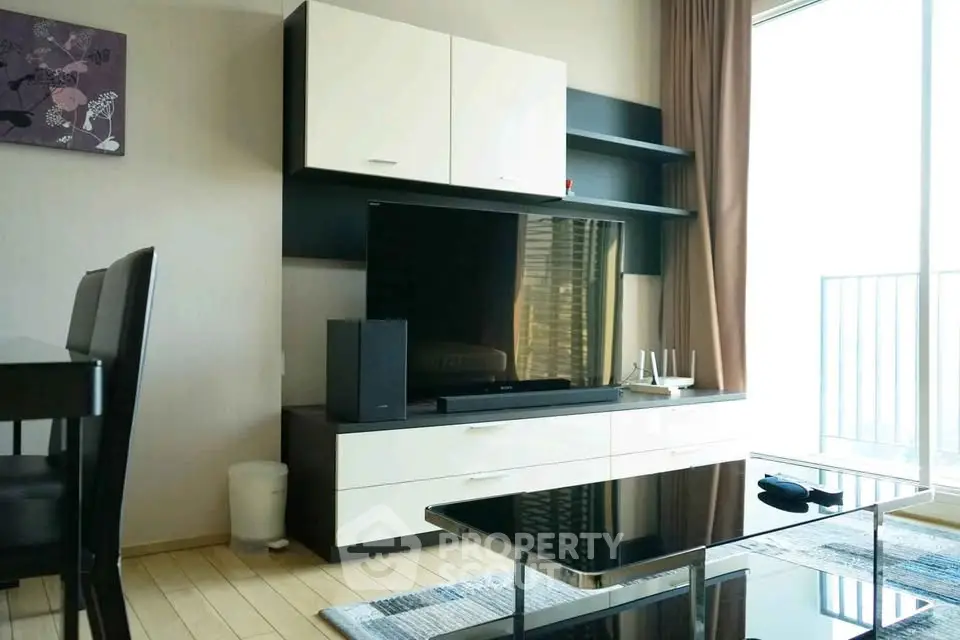 Modern living room with sleek entertainment center and large TV, featuring stylish furniture and natural light.