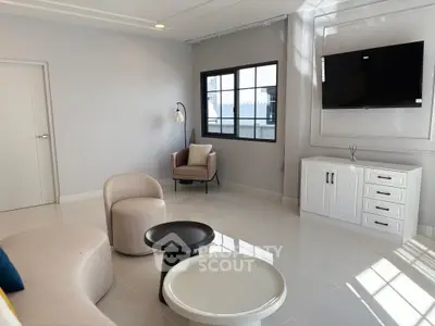 Modern living room with sleek furniture and wall-mounted TV, featuring large windows for natural light.