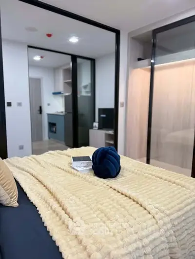 Modern bedroom with cozy decor and view into a compact kitchen area, perfect for urban living.