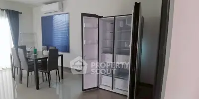 Modern dining area with open double-door fridge and sleek furniture.