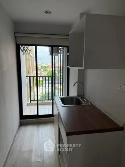Compact kitchen with balcony view in modern apartment