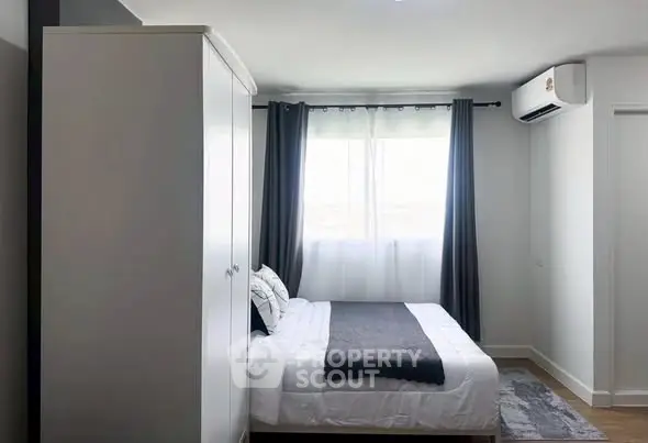 Modern bedroom with sleek design, featuring a cozy bed, wardrobe, and air conditioning unit.