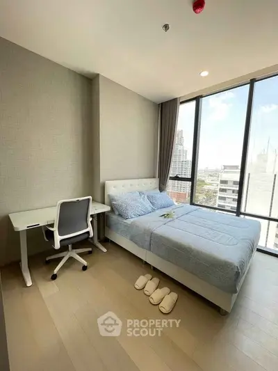 Modern bedroom with city view, featuring a cozy bed and a sleek study desk.