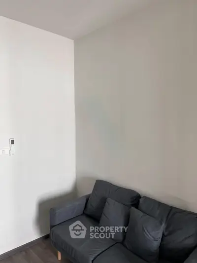 Cozy minimalist living room with modern gray sofa and sleek white walls.
