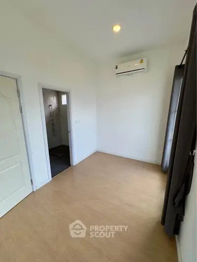 Spacious empty room with air conditioning and adjacent bathroom, ideal for customization.