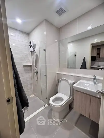 Modern bathroom with glass shower and sleek fixtures in contemporary apartment.