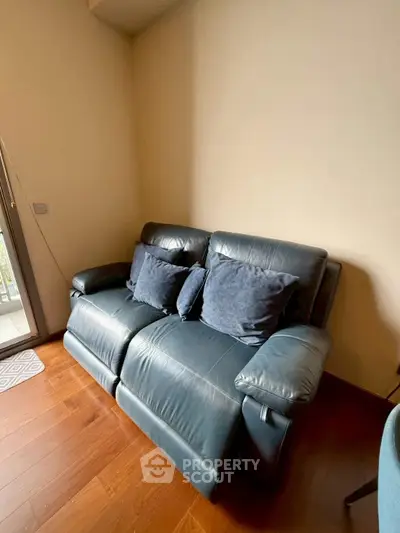 Cozy living room with stylish leather sofa and wooden flooring, perfect for relaxation.