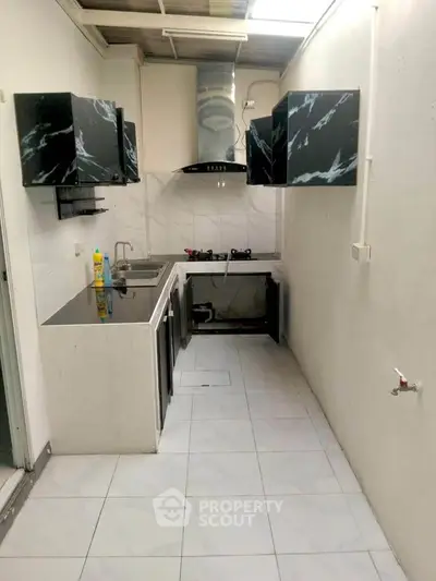 Modern kitchen with sleek black cabinets and gas stove in compact layout.