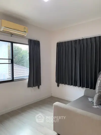 Bright living room with large windows and modern air conditioning unit.