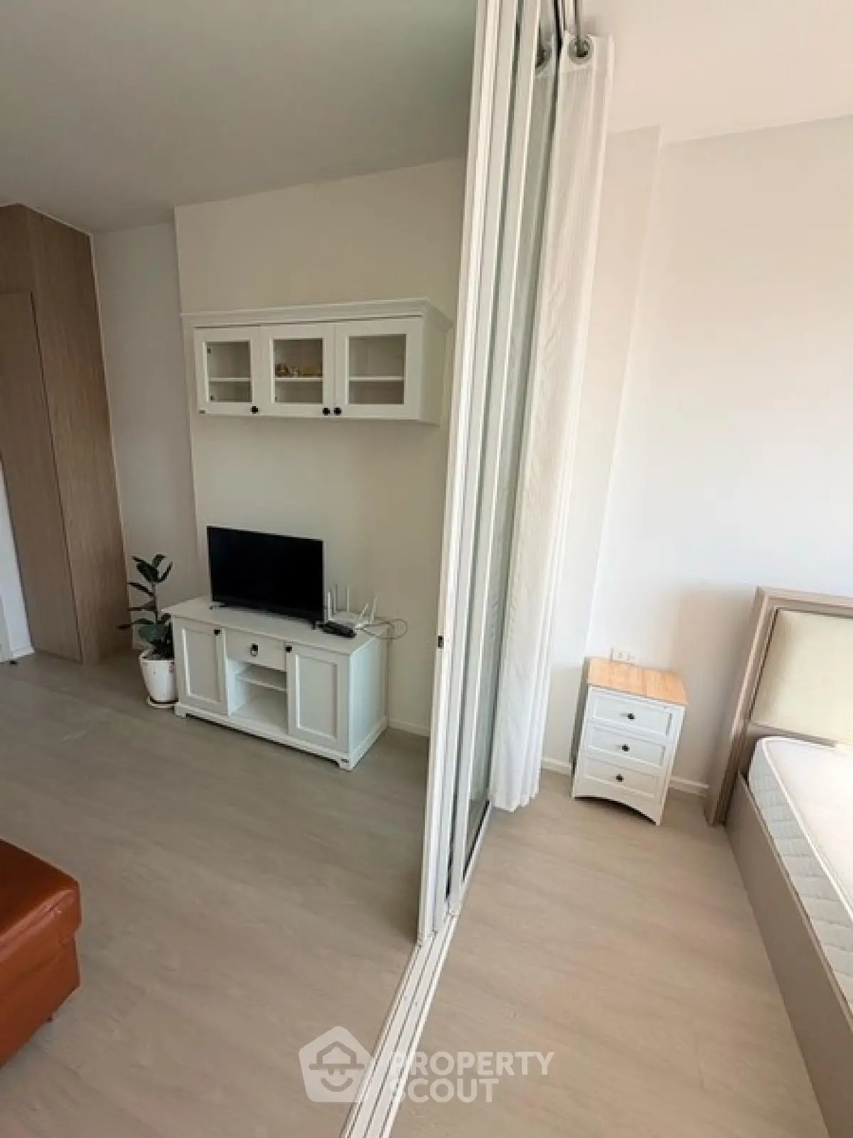 Modern studio apartment with partitioned living and sleeping areas, featuring sleek furniture and natural light.