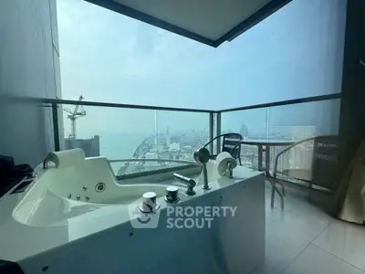 Luxurious balcony with jacuzzi offering stunning city and ocean views.