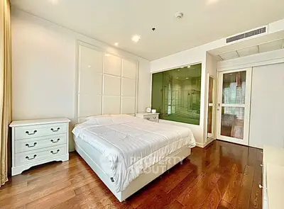 Spacious modern bedroom with elegant wooden flooring and stylish white furniture.
