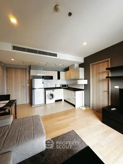 Modern open-plan living room with kitchen featuring sleek appliances and cozy seating area.
