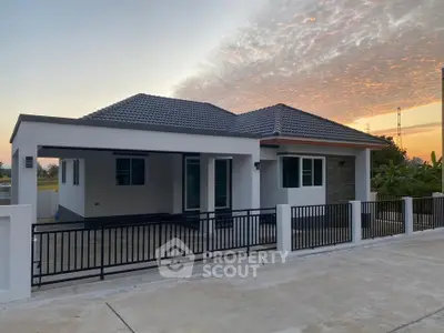 Modern single-story house with sleek design and spacious driveway at sunset.