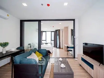 Modern living room with stylish furniture and open view to bedroom, featuring sleek decor and natural light.