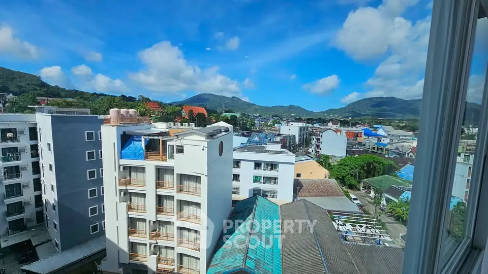 Stunning cityscape view from high-rise building window with mountains in the background.