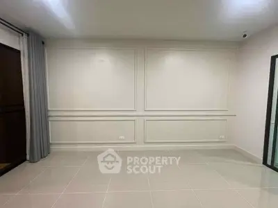 Spacious empty room with elegant wall paneling and large tiles, perfect for customization.
