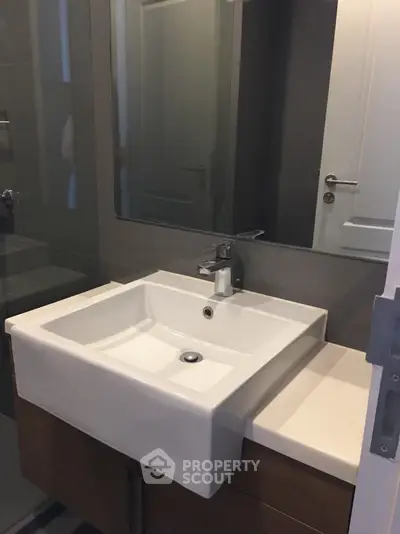 Modern bathroom with sleek sink and mirror in contemporary apartment.