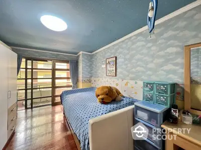 Cozy bedroom with hardwood floors, whimsical sky-themed wallpaper, and direct balcony access, perfect for comfortable living.