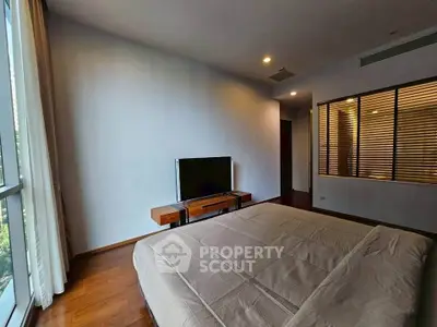 Spacious bedroom with large window and modern decor in a luxury apartment.