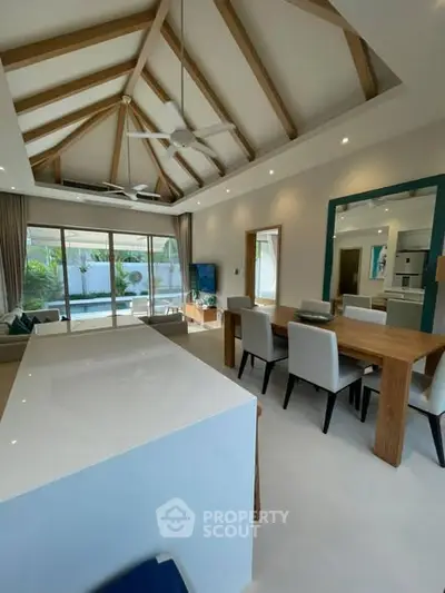 Spacious modern living room with vaulted ceiling and open layout, featuring elegant dining area and garden view.